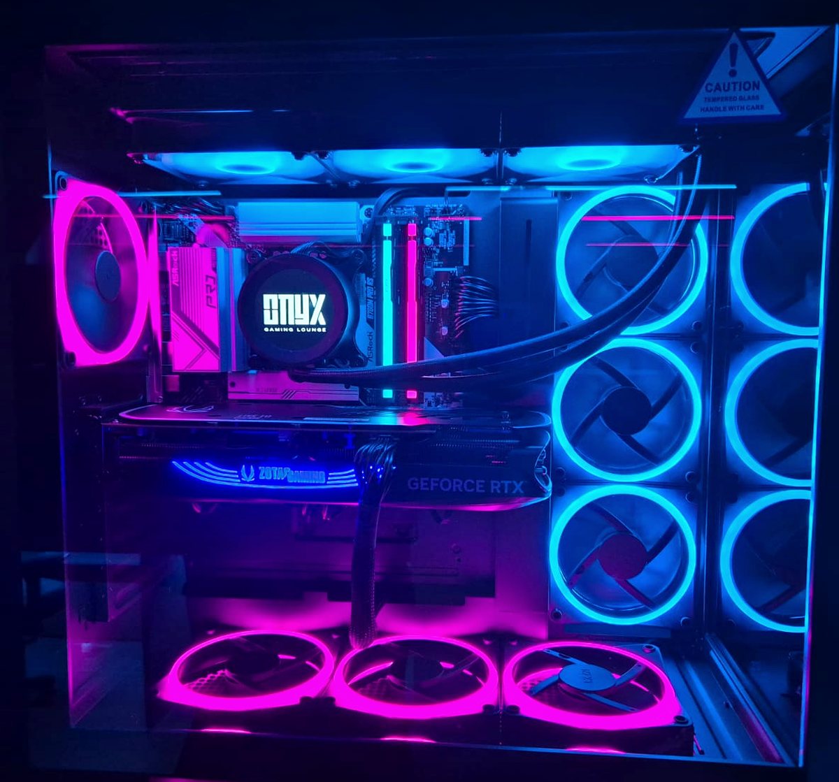 Interior of a gaming lounge PC showing a liquid cooler, GeForce RTX graphics card and nine ring-lit fans behind tempered glass