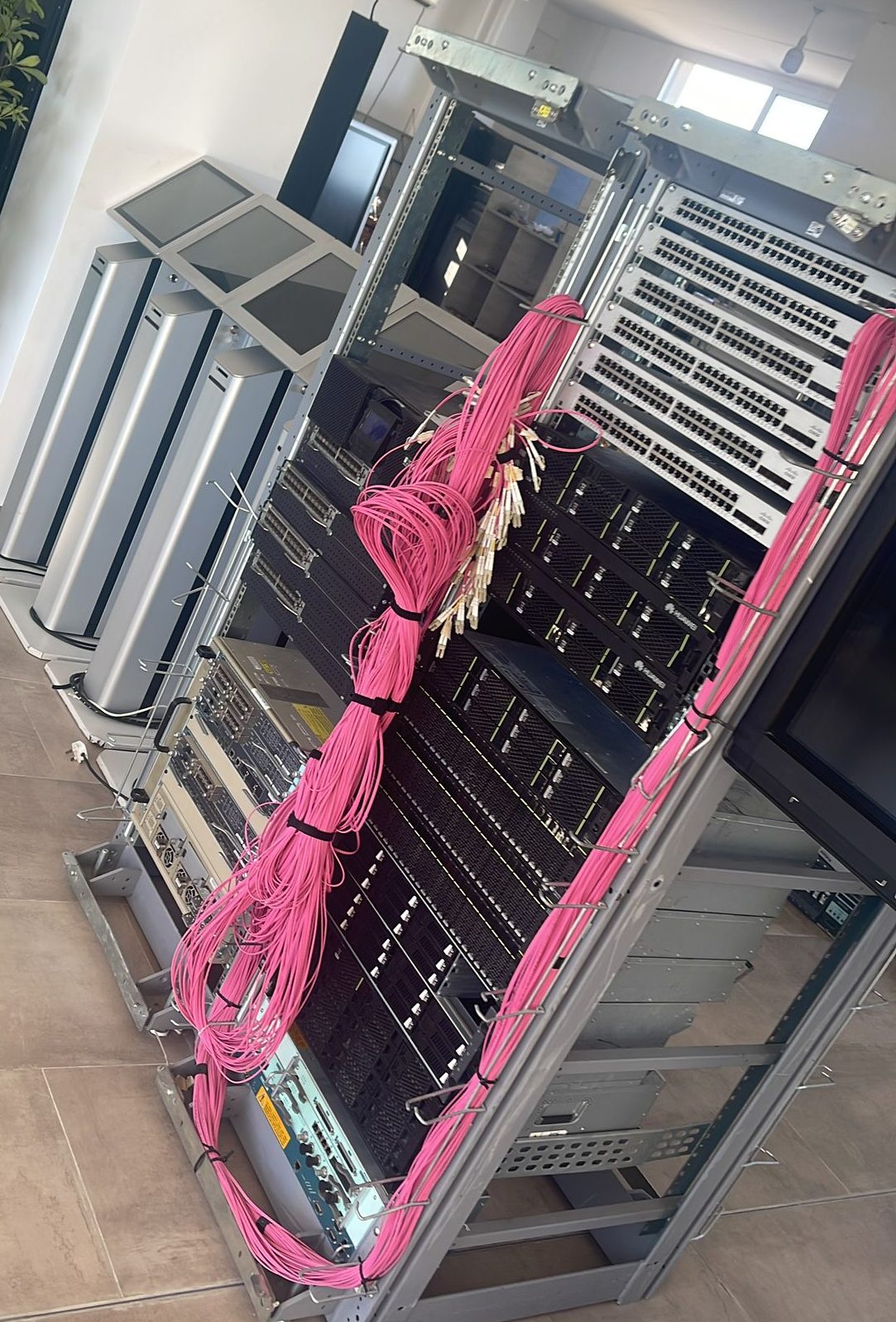 Server room racks with bundled pink fibre trunks running to patch panels above blade chassis